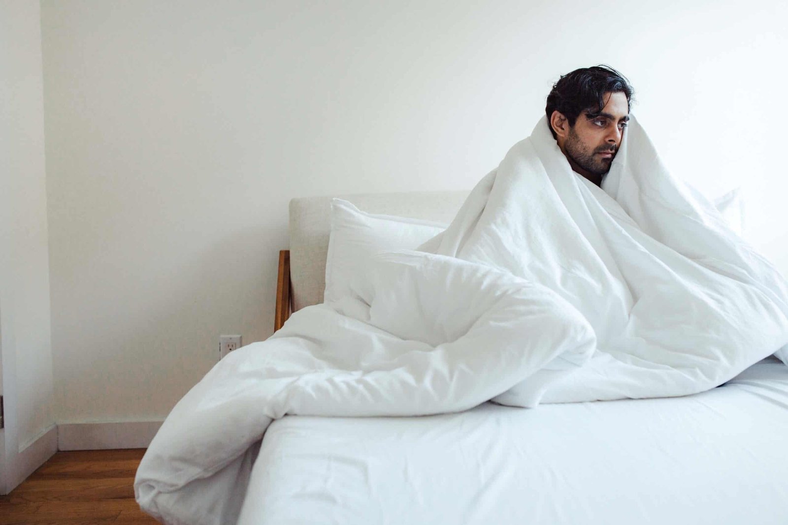 man wrapped in a duvet in bed