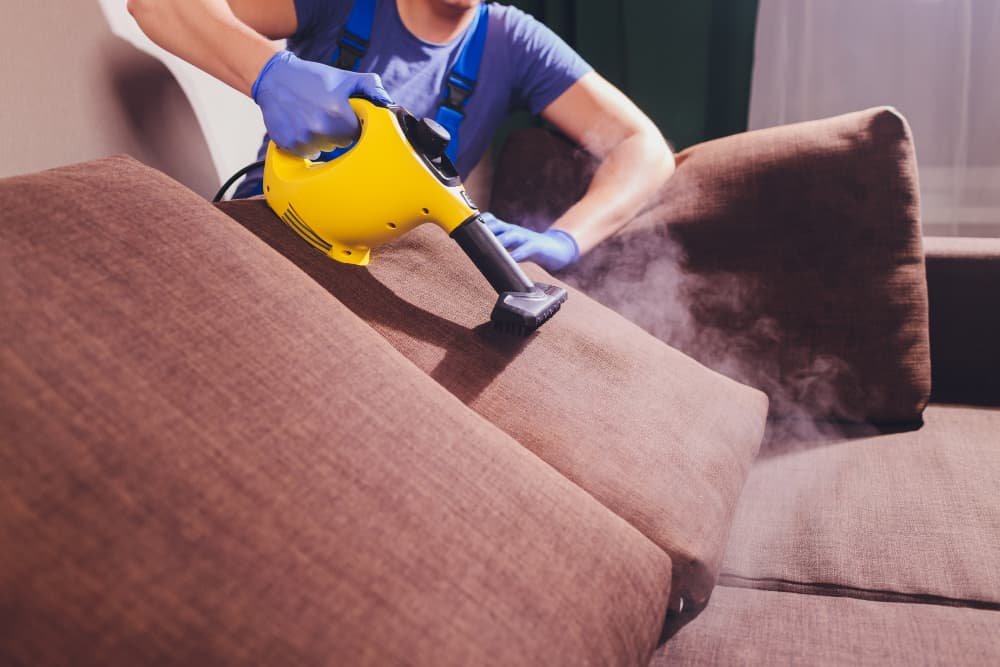 person using a hoover to clean a sofa