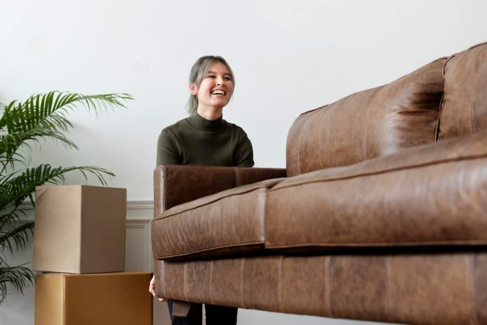 women carrying a brown sofa